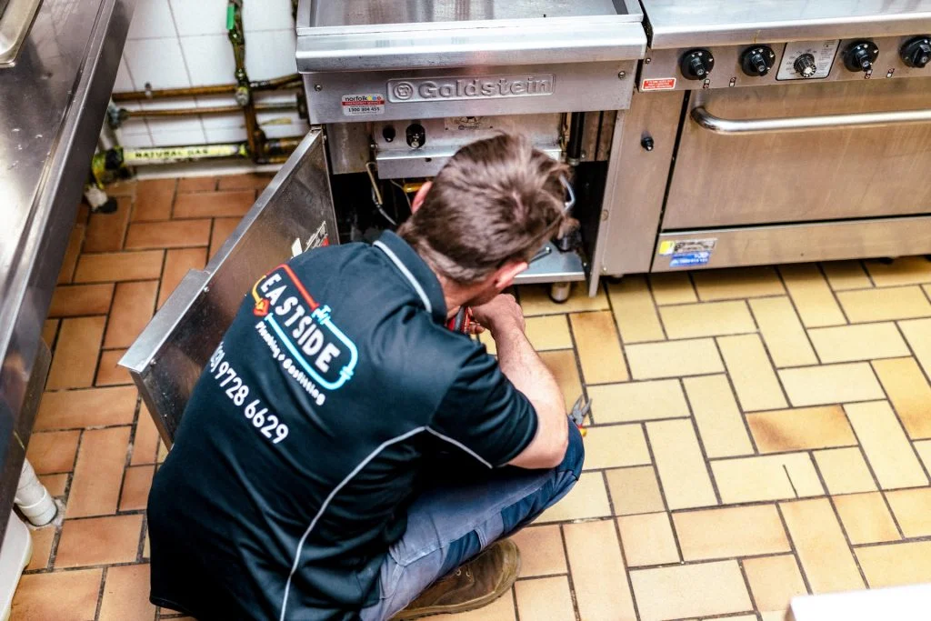 Professional plumber working in commercial kitchen